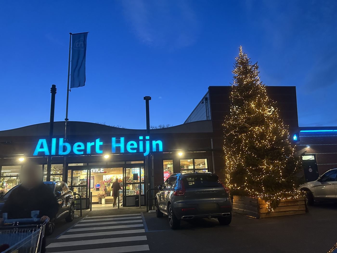 Een verlichte XL-kerstboom bij de ingang van een Albert Heijn